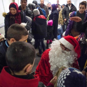Voluntário vestido de Papai Noel distribui presentes para filhos de refugiados, na Alemanha