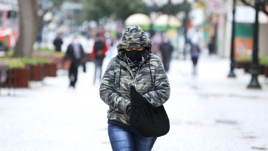 21.ago.2020 - Mulher se protege do frio enquanto caminha por ruas de Curitiba - Giuliano Gomes/Estadão Conteúdo