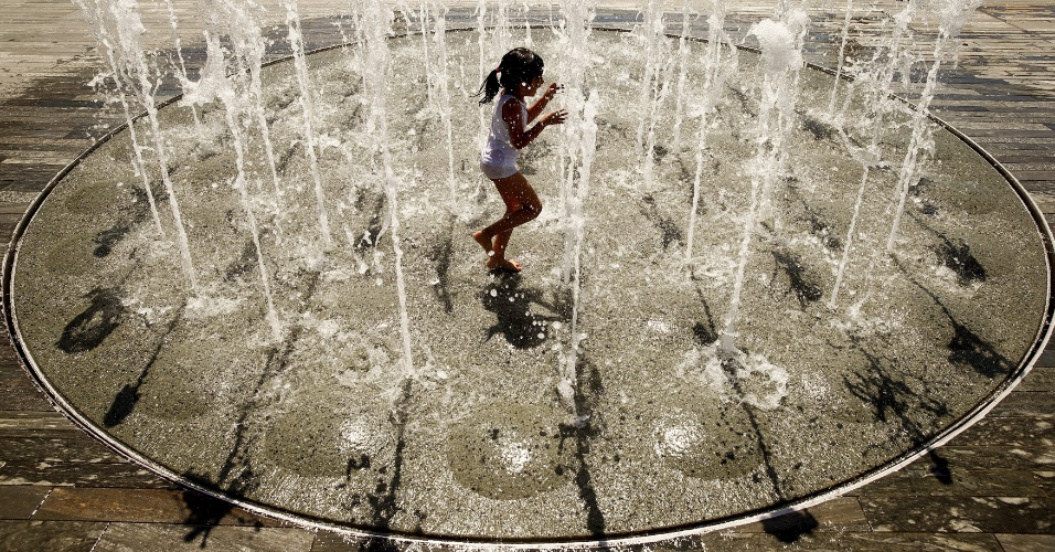 30.ago.2015 - Garota brinca com água de fonte da praça Sechselaeutenplatz, durante dia com altas temperaturas, em Zurique, (Suíça)