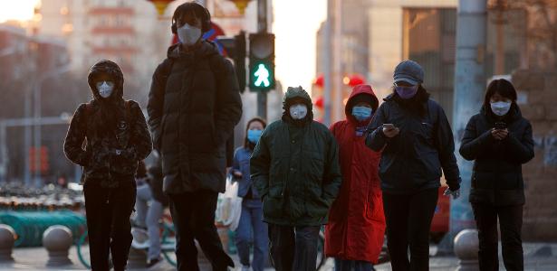 Pessoas com máscara de proteção em rua de Pequim