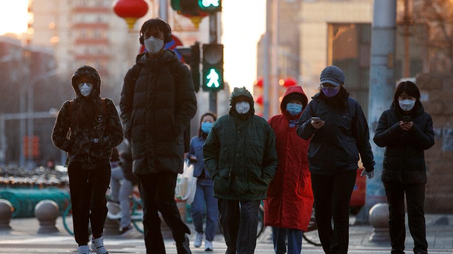 Pessoas com máscara de proteção em rua de Pequim, na China - THOMAS PETER