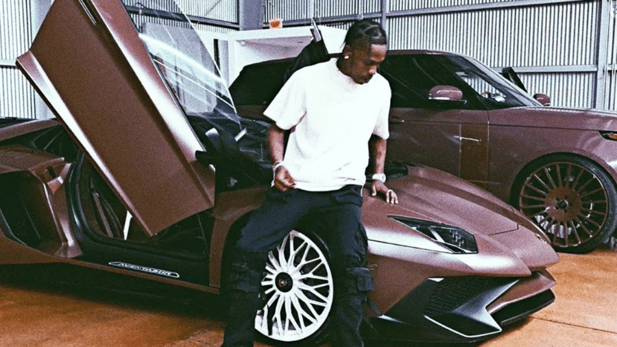 Travis Scott com dois de seus veículos de luxo. Com uma predileção pela cor marrom, o rapper envelopa seus carros com o mesmo tom terroso