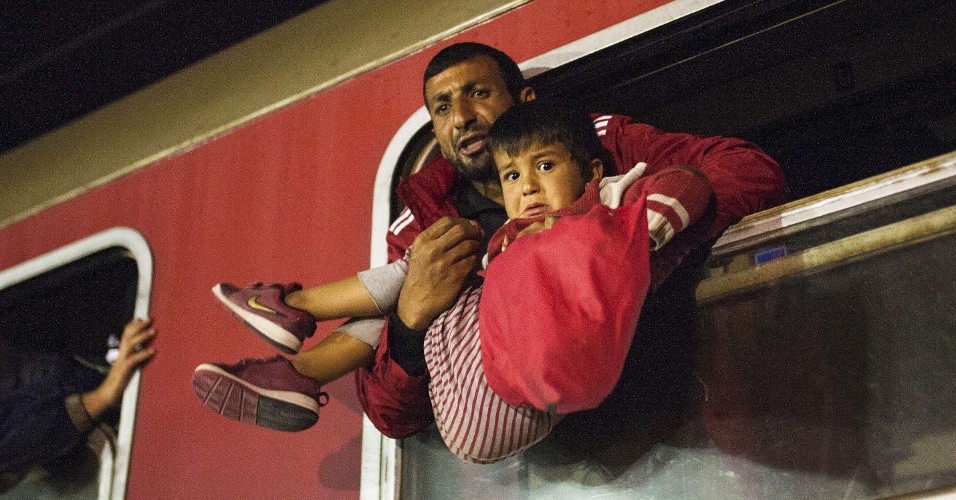 7.out.2015 - Homem segura criança em janela de trem que segue para a Sérvia a partir de Gevgelija, na fronteira entre Grécia e Macedônia. A Macedônia é um país de trânsito crucial na rota de migração de refugiados, muitos deles vindos da Síria, Afeganistão, Iraque e Somália na tentativa de conseguir asilo na Europa