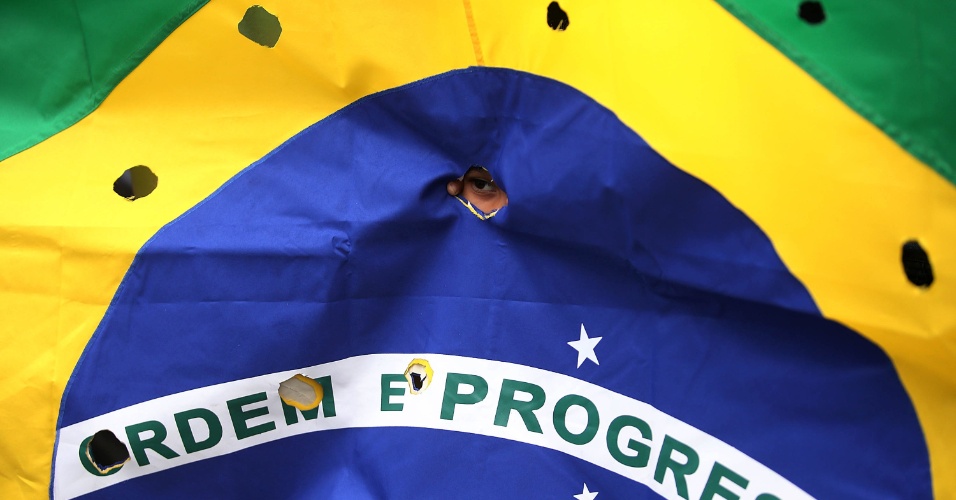 30.nov.2015 - Bandeira do Brasil furada, em alusão a marcas de tiros, foi uma das formas de protesto durante o enterro de cinco jovens assassinados por PMs no Rio de Janeiro. O veículo onde os rapazes estavam foi atingido por mais de 50 disparos de fuzil