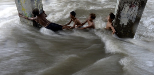 Crianças brincam em rua inundada em Manila, nas Filipinas - Noel Celis/AFP