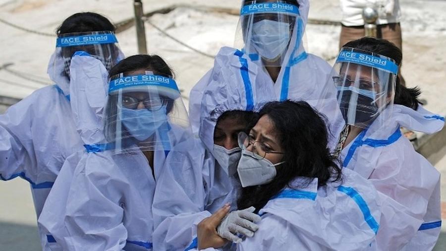 Grupo de trabalhadoras da saúde com equipamento de proteção individual se abraça - Reuters