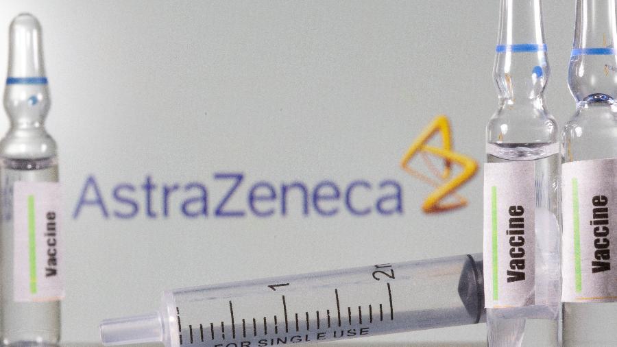 Tubo de ensaio rotulado como de vacina para Covid-19 à frente de logo da AstraZeneca em foto de ilustração - 