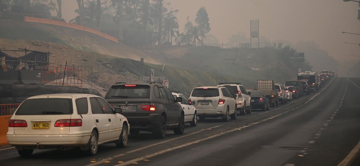 2.jan.2020 - Com céu tomado por fumaça de incêndios florestais, carros formam fila na saída de Batemans Bay, no estado de Nova Gales do Sul, na Austrália - Peter Parks/AFP