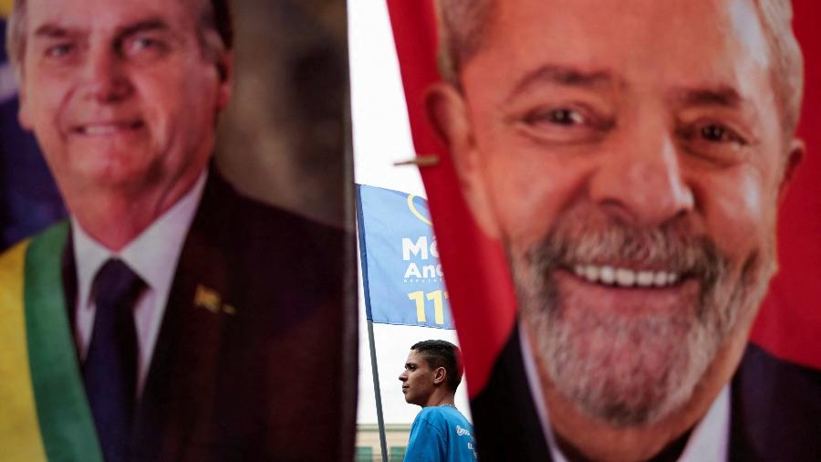Homem passa por trás de toalhas com rostos de Lula e Bolsonaro, que estão a frente das pesquisas  - Ueslei Marcelino/Reuters