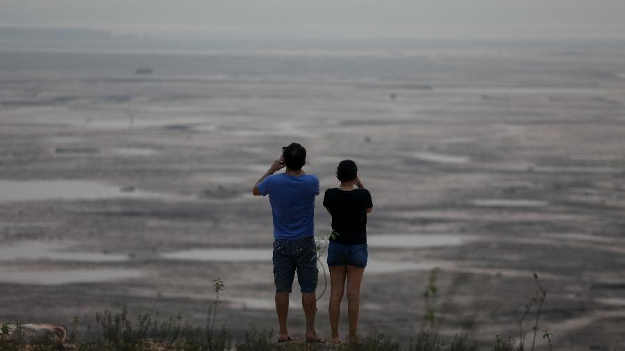 Margem seca do rio Negro em Manaus, coberta pela fumaça de incêndios florestais