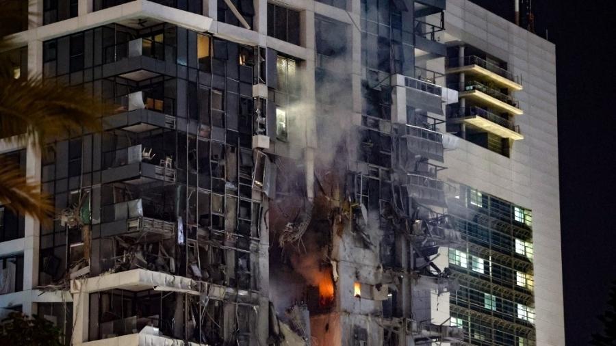 13.jun.2025 - Fogo e fumaça sobem de um prédio, supostamente atingido por um míssil disparado do Irã, no centro de Tel Aviv, em 13 de junho de 2025. O Irã disparou uma barragem de mísseis balísticos contra Israel em um contra-ataque - Jack GUEZ / AFP