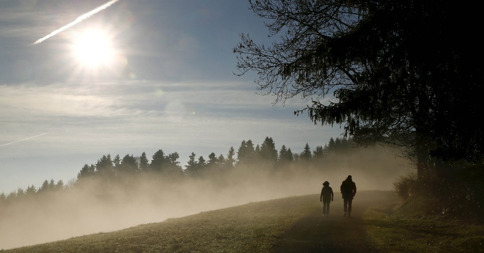 12.nov.2015 - Pedestres atravessam uma floresta com o sol brilhando sobre a névoa perto da passagem da montanha Albis Passe, na Suíça