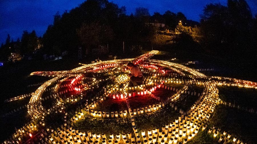 Arrumadas em formato de cruz, as velas pretendem homenagear as pessoas mortas pela covid-19 - AFP