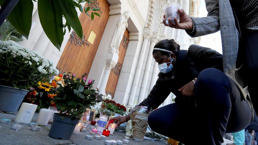 Várias pessoas colocaram flores e velas em frente à Basílica de Notre-Dame, em Nice, em homenagem às vítimas do atentado que deixou três mortos no local - Valery Hache/AFP