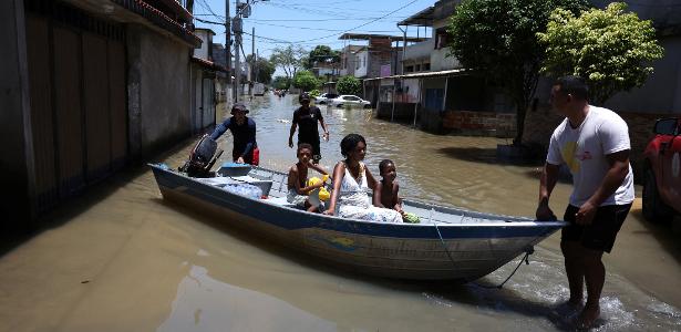 Moradores são transportados de barco em rua alagada após fortes chuvas em Duque de Caxias, no Rio de Janeiro