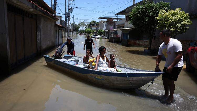 Pessoas são levadas de barco em rua alagada após fortes chuvas em Duque de Caxias, Rio de Janeiro