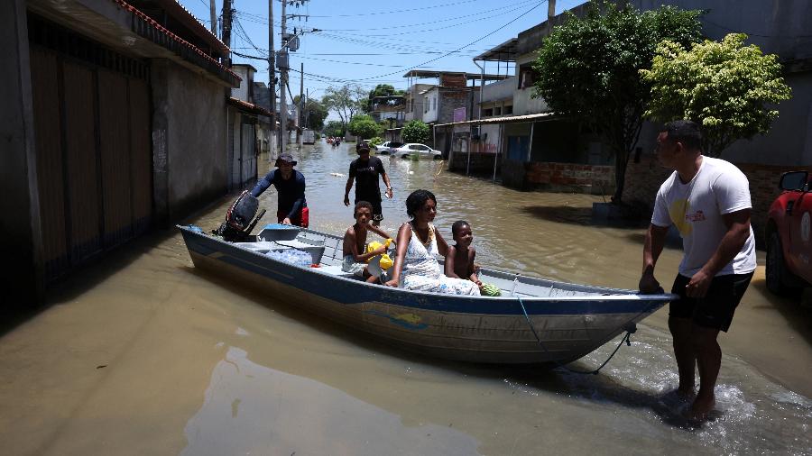 Moradores são transportados de barco em rua alagada após chuvas em Duque de Caxias, no Rio de Janeiro