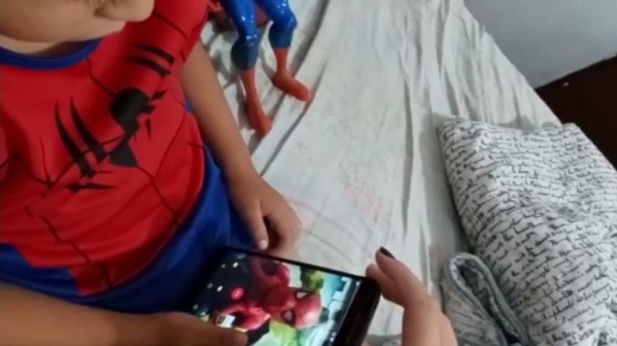 Criança olha o animador de festas infantis José Luís Fernandes caracterizado como Homem-Aranha pelo celular - Arquivo pessoal/ José Luís Fernandes