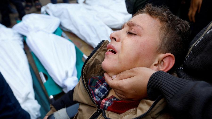 Menino palestino ferido em ataque isralense acompanha o funeral de familiares mortos no conflito em Khan Younis, no sul da Faixa de Gaza