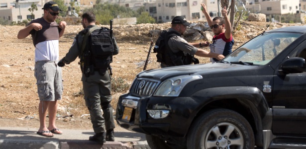 Policiais israelenses revistam palestinos em estrada ligando o bairro palestino de Jabal Mukaber, em Jerusalém Oriental, e Jerusalém - Menahem Kahana/AFP