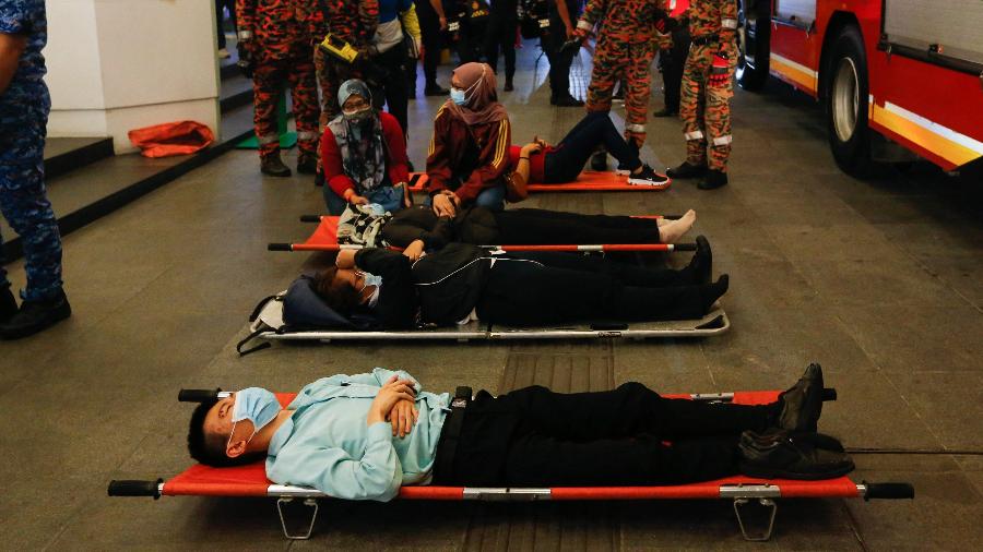 Passageiros feridos deitados em macas fora da estação KLCC após um acidente envolvendo dois trens do Light Rail Transit (LRT) em Kuala Lumpur, na Malásia. - STR / AFP