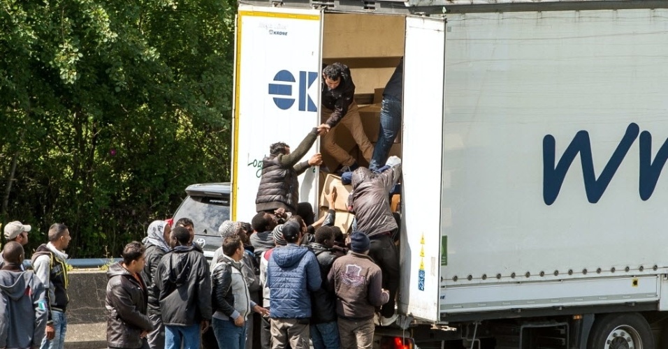 23.jun.2015 - Migrantes sobem na traseira de um caminhão a caminho do Eurotunnel em Calais, no noroeste da França, durante um protesto que bloqueou o acesso às estradas. O objetivo é atravessar o canal da Mancha e chegar ao Reino Unido