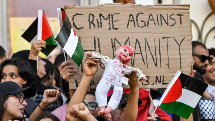 18.out.2023 - Manifestantes seguram boneco representando um bebê enquanto entoam slogans durante uma manifestação contra Israel em frente à sede da embaixada francesa na Tunísia 