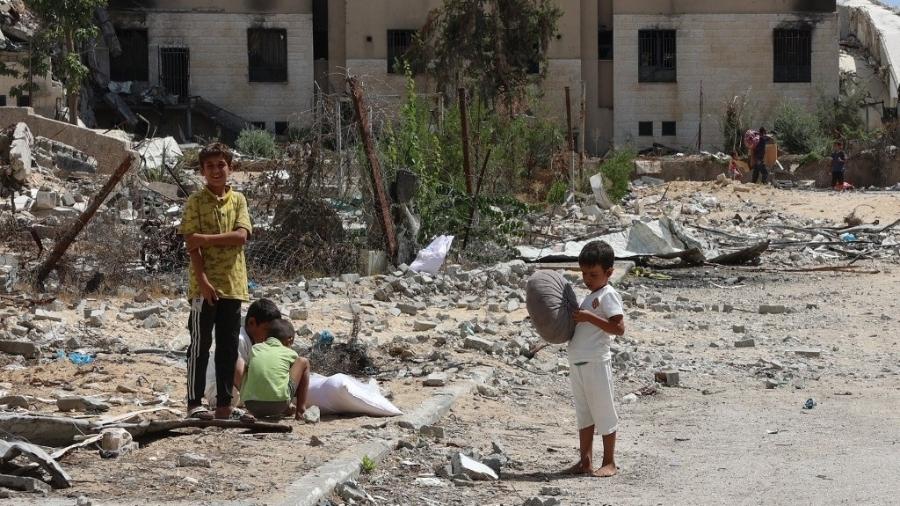 Crianças palestinas se reúnem em frente a prédios danificados pelo bombardeio israelense, em Beit Lahia, no norte da Faixa de Gaza, em 14 de setembro de 2024 - OMAR AL-QATTAA/AFP