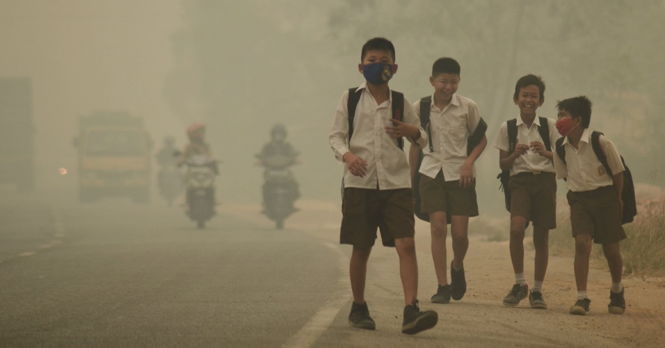 29.set.2015 - Alunos passeiam na rua, liberados da escola para voltar para casa mais cedo devido à neblina em Jambi, na  Indonésia