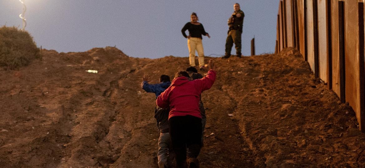 3.dez.2018 - Migrantes da América Central se entregam a agentes da fronteira dos EUA após pular a cerca que separa as cidades de Tijuana e San Diego, na fronteira do México - REUTERS/Alkis Konstantinidis 