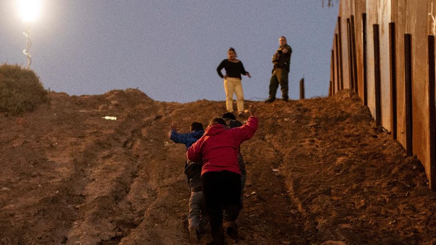3.dez.2018 - Migrantes da América Central se entregam a agentes da fronteira norte-americana após pular a cerca que separa as cidades de Tijuana e San Diego, na fronteira do México com os Estados Unidos - REUTERS/Alkis Konstantinidis 