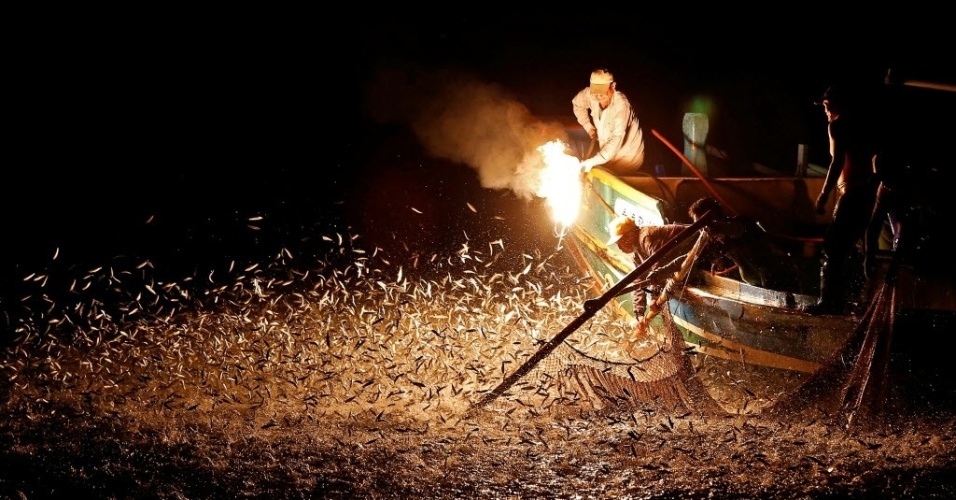 27.jun.2016 - Pescadores usam chamas para atrair peixes em Nova Taipé, Taiwan. Os homens usam um método ancestral e sustentável de pesca em que eles misturam água e enxofre para obter acetileno e produzir luzes que atraem pequenos peixes prateados para fora d'água