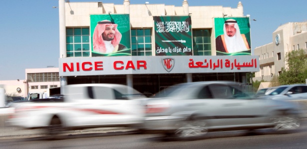 Carros passam diante de imagens do rei saudita Salman bin Abdulaziz Al Saud (dir.) e do príncipe Mohammed bin Salman, em Riad, Arábia Saudita - Faisal Al Nasser/ Reuters