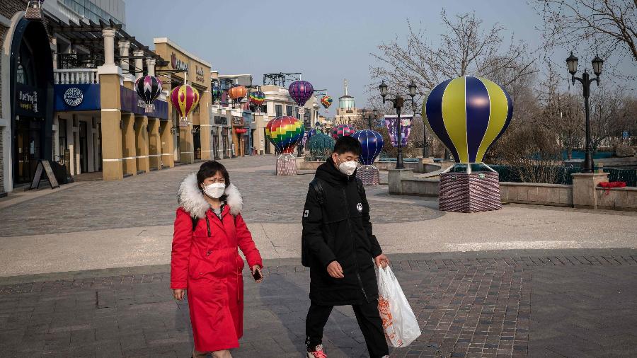 25.fev.2020 - Pessoas usam máscaras como medida preventiva contra o novo coronavírus ao andar em shopping de Pequim - Nicolas Asfouri/AFP