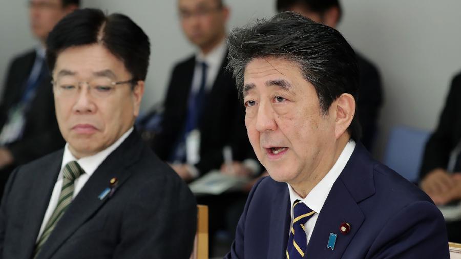 Shinzo Abe (dir.) e ministro da Saúde japonês, Katsunobu Kato (esq.), participam de reunião para conter a disseminação do coronavírus no país - STR/Jiji Press/AFP