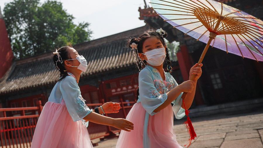 Crianças com máscara brincam perto da entrada da Cidade Proibida, em Pequim - THOMAS PETER