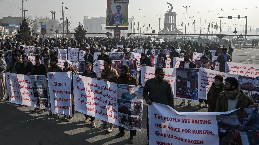 21.dez.21 - Pessoas seguram faixas antes de marchar nas ruas durante um protesto em Cabul; o Afeganistão enfrenta uma profunda crise econômica - MOHD RASFAN/AFP