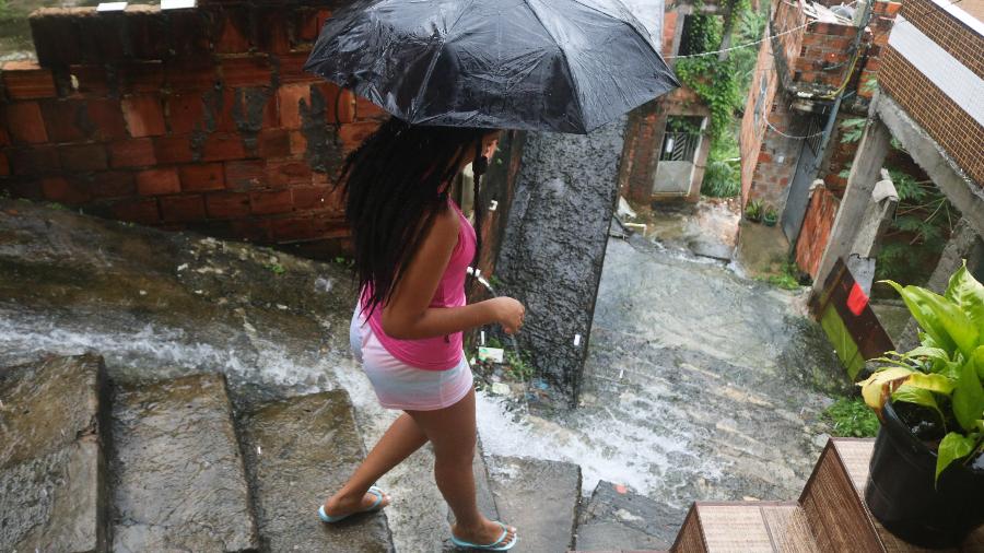 Mulher com guarda-chuva desce escadarias em meio à enxurrada, no bairro Novo Horizonte, em Salvador - Mauro Akiin Nassor/Fotoarena/Folhapress