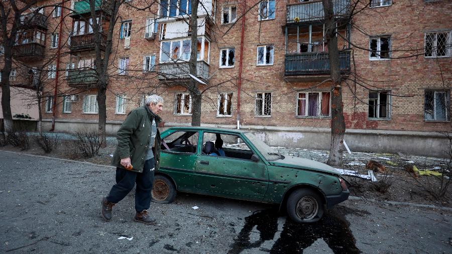 23.mar.2022 - Um homem passa por um carro e um prédio danificados em um ataque militar, em meio à invasão da Ucrânia pela Rússia, em Kiev, na Ucrânia. - SERHII NUZHNENKO/REUTERS