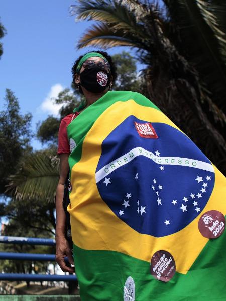 24.jul.2021 - Manifestante enrolada em bandeira do Brasil durante protesto contra o governo federal no Recife - Arnaldo Sete/FuturaPress/Estadão Conteúdo