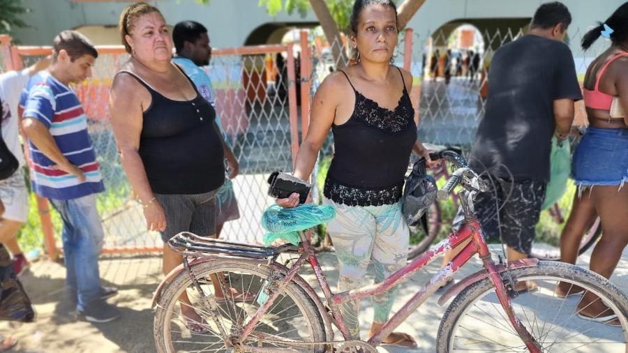 4.abr.2022 - Com a bicicleta enlameada, Amanda Santos espera em fila ajuda a vítimas das chuvas em Belford Roxo - Igor Mello/UOL