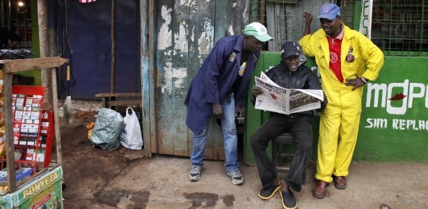 Homens, no bairro de Kibera, em Nairóbi, leem matéria de jornal - Till Muellenmeister/AFP