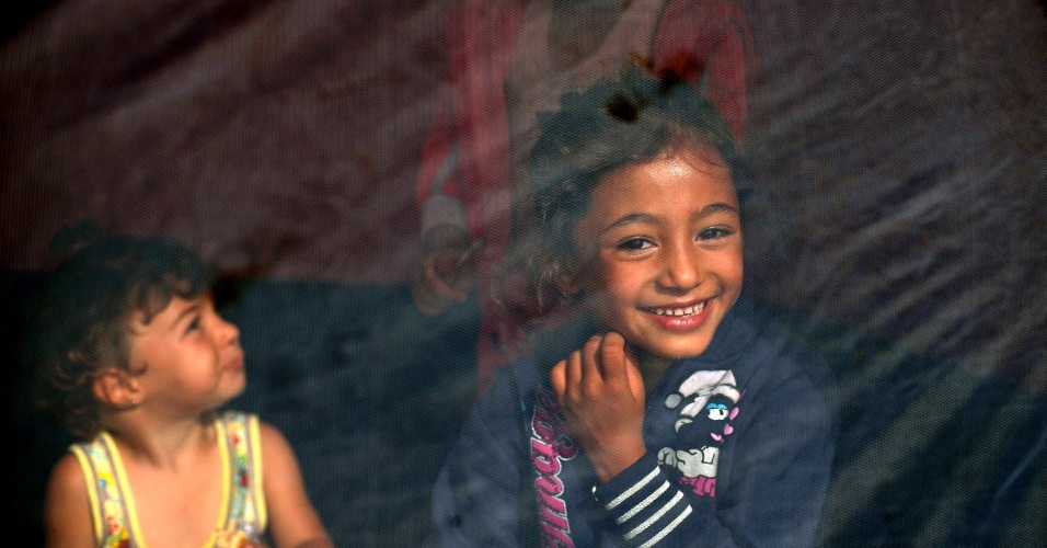 17.set.2015 - Menina imigrante sorri sentada dentro de uma tenda perto da fronteira entre a Sérvia e a Hungria