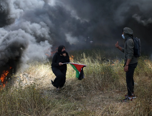 Mulher segura bandeira da Palestina durante protesto na fronteira entre Gaza e Israel - Ibraheem Abu Mustafa/Reuters