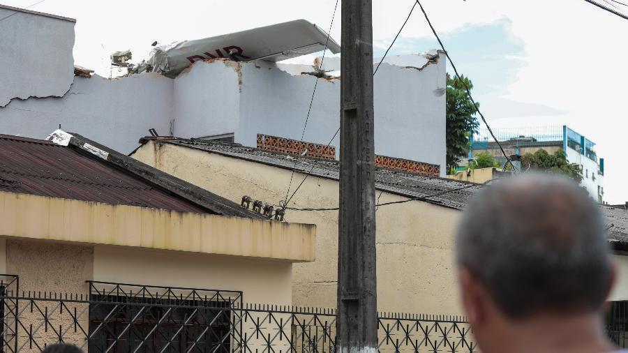 Morador observa destroços de avião de pequeno porte que caiu sobre casa em região residencial de Belém logo após a decolagem - Filipe Bispo/ Foto Arena/Estadão Conteúdo