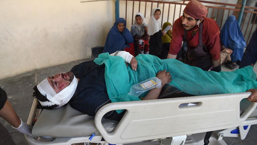 Um homem ferido é levado ao hospital após um atentado próximo a um comício do presidente do Afeganistão, Ashraf Ghani - Wakil Kohsar/AFP
