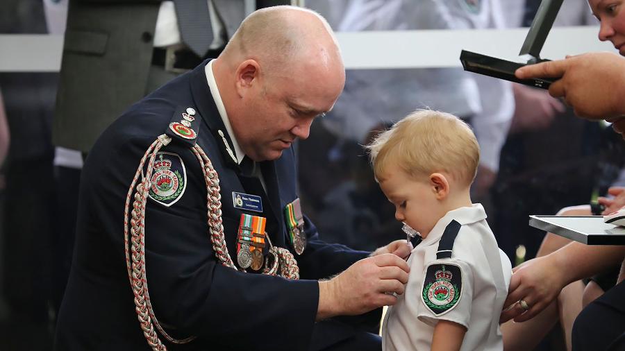 Foto divulgada pelo Serviço Rural de Bombeiros da Nova Gales do Sul mostra comissário fixando uma medalha no bebê Harvey Keaton, que usava chupetas - AFP PHOTO / New South Wales Rural Fire Service