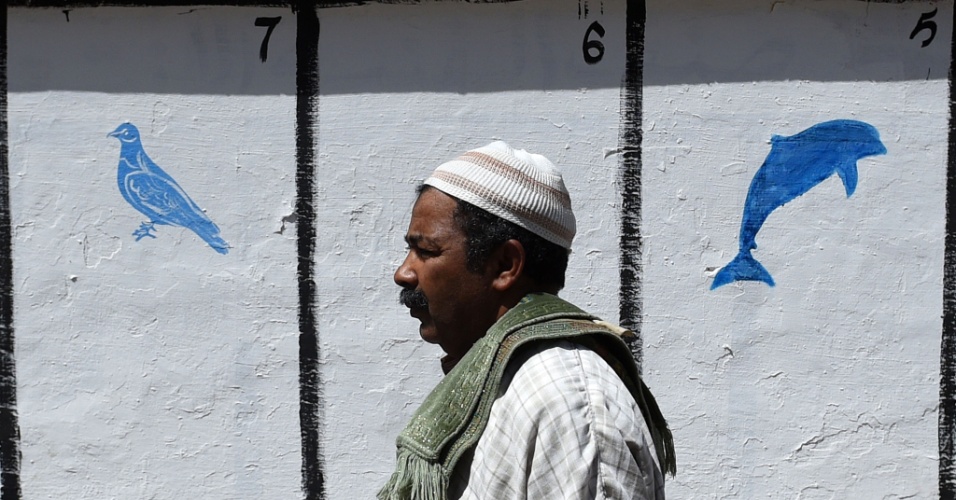 4.set.2015 - Homem passa por uma parede em que estão pintados os símbolos dos partidos candidatos às eleições locais, no centro de Rabat, no Marrocos