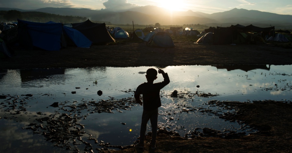 30.abr.2016 - Garoto joga pedras em poça em acampamento de refugiados na fronteira entre a Grécia e a Macedônia. Ao redor de 54 mil pessoas estão retidas na Grécia desde que a rota de migração pelo Bálcãs foi fechada, em fevereiro