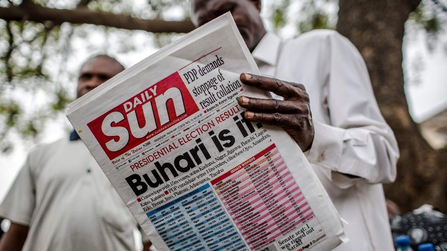 27.fev.2019 - Homem lê jornal que anuncia a reeleição do presidente da Nigéria, Muhammadu Buhari, em Kano - Luis Tato/AFP